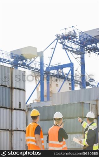 Rear view of workers inspecting cargo containers in shipping yard