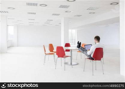 Rear view of young businessman using laptop at new office