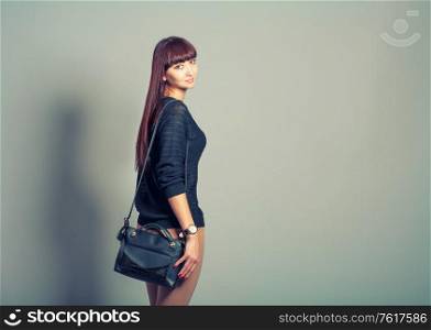 Rear view of young casual woman in pants look back on gray background, toned image. Rear view of young casual woman in pants look back