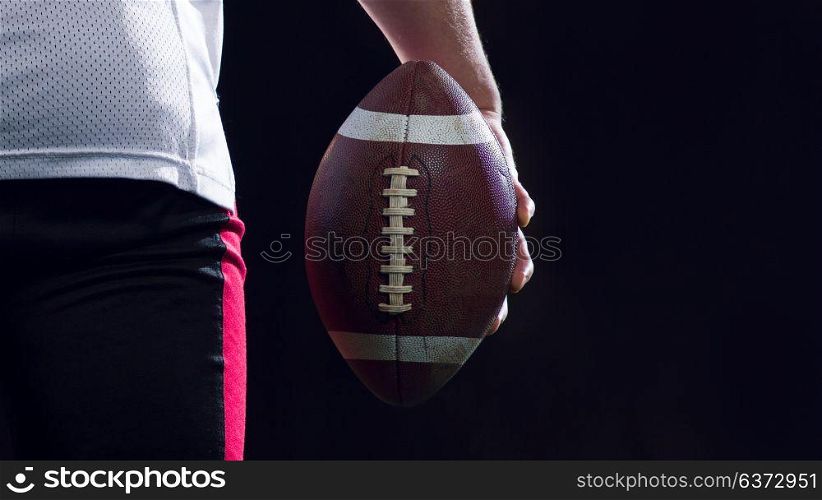 rear view of young confident American football player on field at night