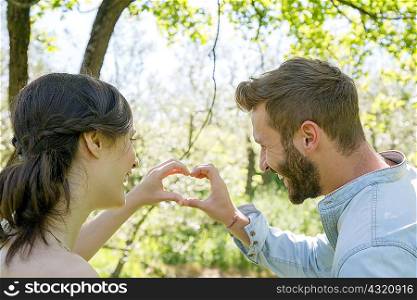 Rear view of young couple making heart shape with hands