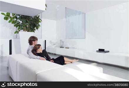 Rear view of young couple on sofa watching TV in living room