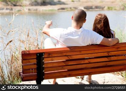 Rear view of young couple seated at the wooden bench