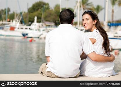 Rear view of young couple sitting at the harbour,focusing on woman
