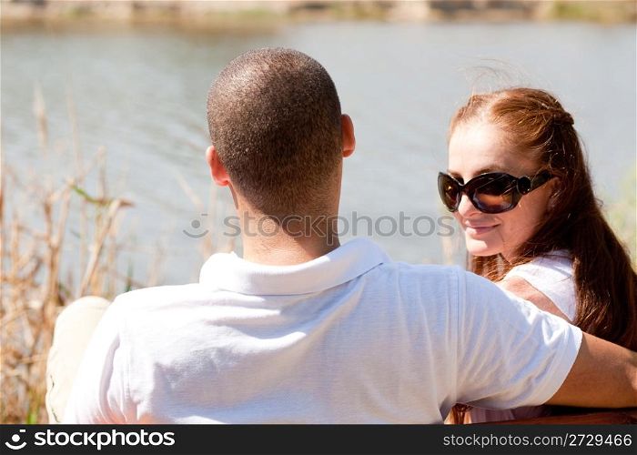 Rear view of young couple sitting at the lake side,focusing on woman