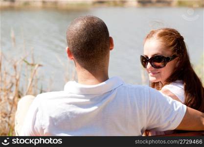 Rear view of young couple sitting at the lake side,focusing on woman