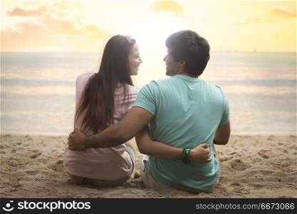 Rear view of young couple sitting together on beach