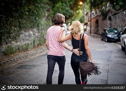 Rear view of young couple strolling on suburban street