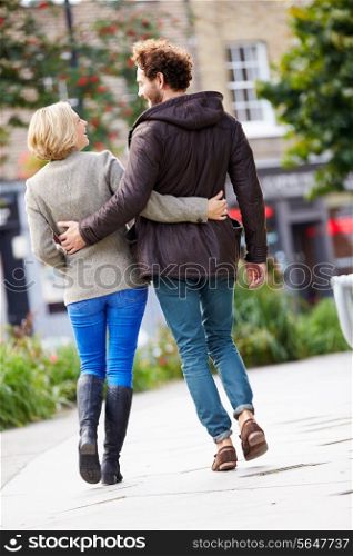 Rear View Of Young Couple Walking Through City Park Together