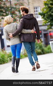 Rear View Of Young Couple Walking Through City Park Together