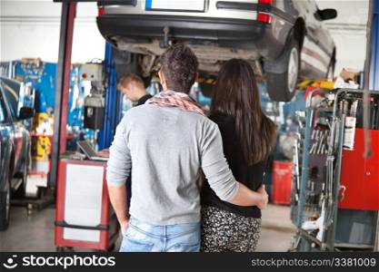 Rear view of young couple with mechanic in the background