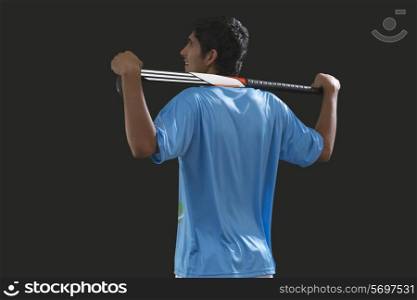 Rear view of young hockey player with stick isolated over black background