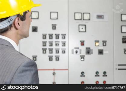 Rear view of young male supervisor examining control room in industry