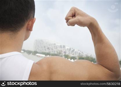 Rear view of young man flexing his bicep, tilt