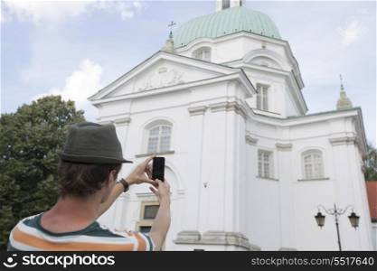 Rear view of young man photographing St. Casimir Church; Warsaw; Poland