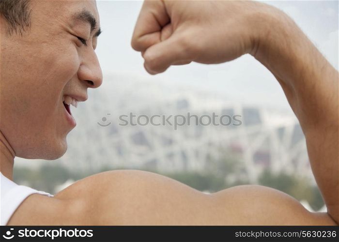 Rear view of young man smiling and flexing his bicep