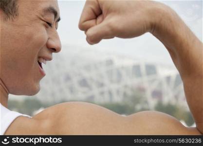 Rear view of young man smiling and flexing his bicep