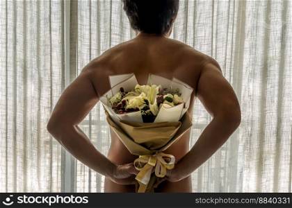 Rear view of Young naked man holding a bouquet of flowers behind his back with white curtains background on the balcony. Love and romance relationships concept, No focus, Specifically.