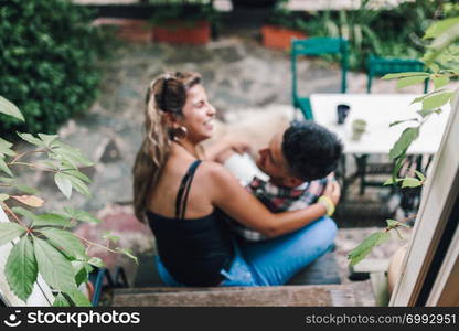 Rear view of young smiling couple sitting on the steps outside the wooden hut