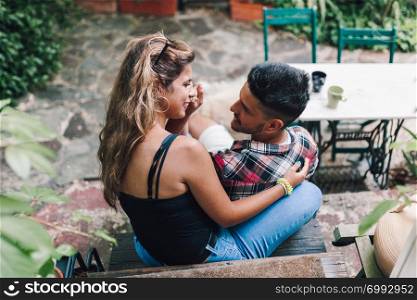 Rear view of young smiling couple sitting on the steps outside the wooden hut