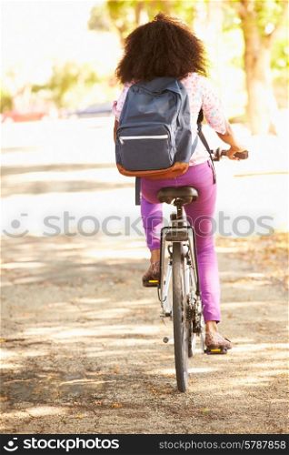 Rear View Of Young Woman Cycling Along Street To Work