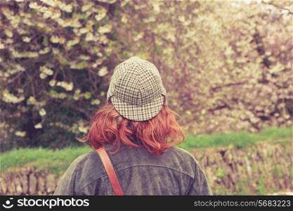 Rear view of young woman in deerstalker hat looking at trees
