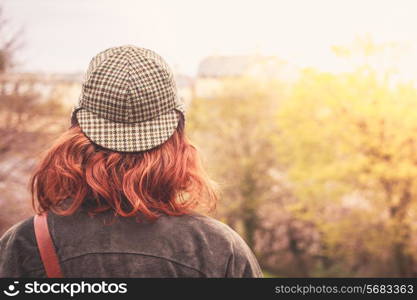 Rear view of young woman in deerstalker hat looking at trees
