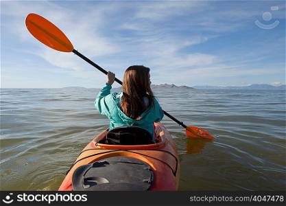Rear view of young woman kayaking, holding paddles, Great Salt Lake, Utah, USA