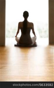 Rear view of young woman meditating on floor
