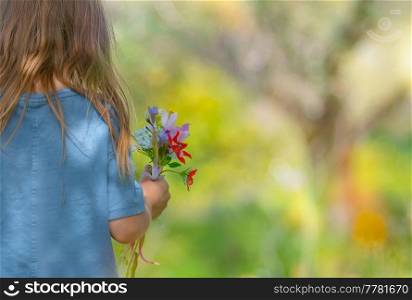 Rear View on a Cute Little Kid with Bouquet of Wildflowers. Having Fun on Beautiful Floral Meadow. Enjoying Fresh Spring Nature.. Happy Child on the Floral Field