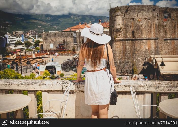 Rear view photo of beautiful woman wearing hat looking at old city