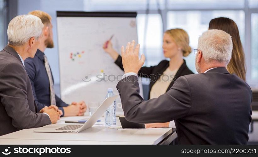 rear view senior businessman asking questions during presentation