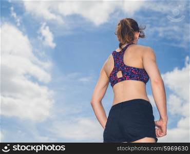 Rear view shot of a fit young woman against a clear blue sky