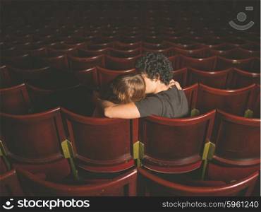 Rear view shot of a young couple sitting in a movie theater and kissing