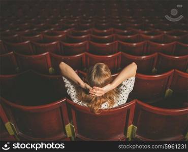 Rear view shot of a young woman sitting alone in an auditorium