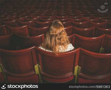 Rear view shot of a young woman sitting alone in an auditorium