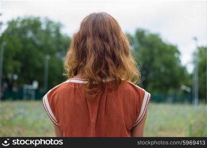Rear view shot of a young woman standing in a park