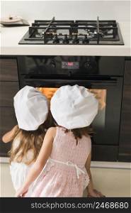 rear view two kids chef hat looking cookie tray oven
