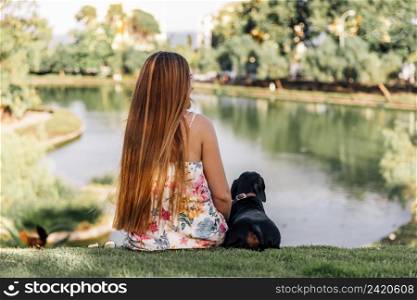 rear view woman dachshund sitting near pond