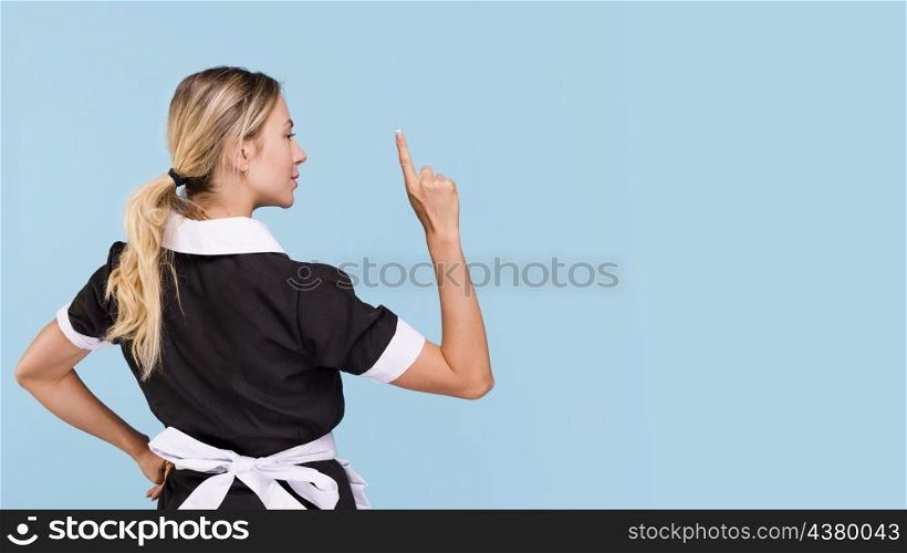rear view woman pointing upwards standing against blue background