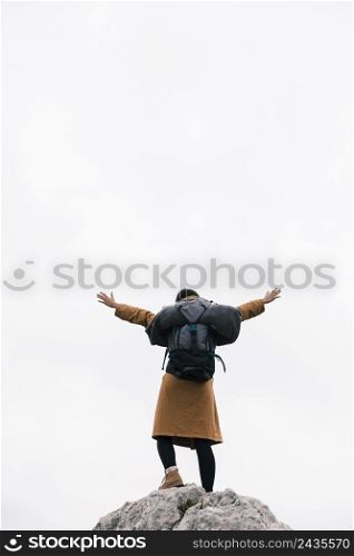 rear view woman standing top mountain raising her arms against sky