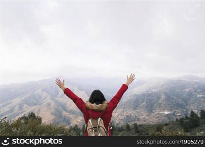 rear view woman with backpack raising her arms overlooking mountain landscape. Beautiful photo. rear view woman with backpack raising her arms overlooking mountain landscape