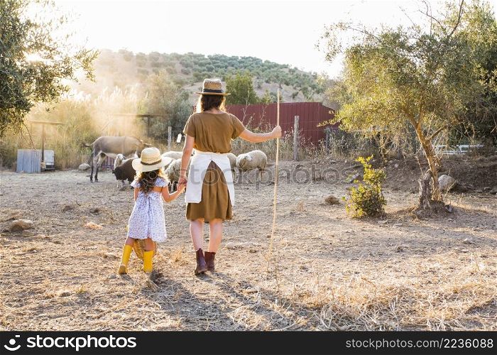 rear view woman with her daughter looking animals field