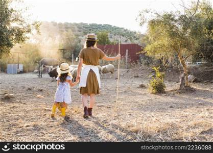rear view woman with her daughter looking animals field