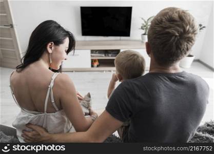 rear view young couple sitting with their dog baby boy watching television