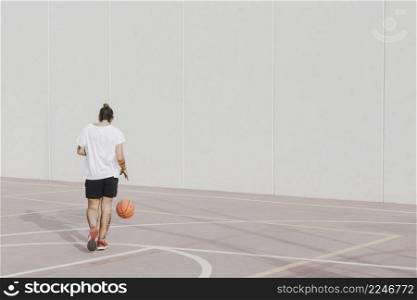 rear view young man praticing basketball