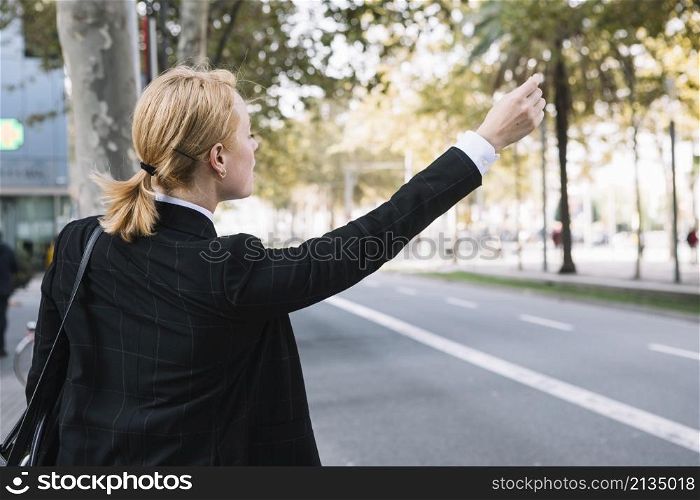 rear view young woman hailing rideshare taxi car road