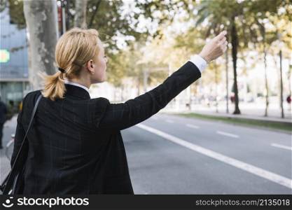 rear view young woman hailing rideshare taxi car road