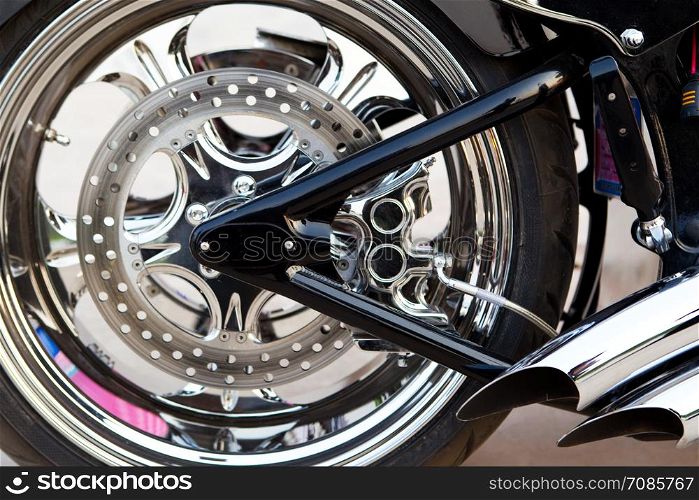 Rear wheel detail of motorcycle with brake pads and part of exhaust pipe