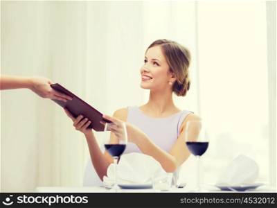 reastaurant and happiness concept - smiling young woman giving menu to waiter at restaurant. smiling woman giving menu to waiter at restaurant